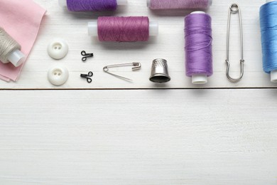Photo of Flat lay composition with thimble and different sewing tools on white wooden table. Space for text