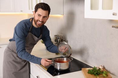 Photo of Man cooking delicious tomato soup in kitchen
