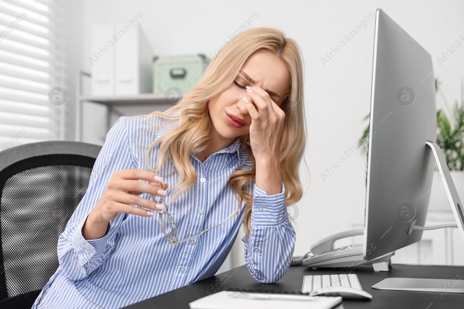 Photo of Overwhelmed woman with glasses at table in office