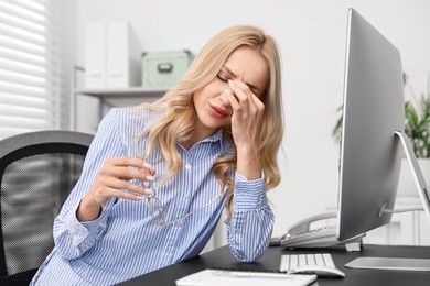 Overwhelmed woman with glasses at table in office