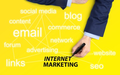 Internet marketing. Different words and businessman with marker on yellow background, top view