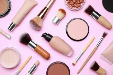 Photo of Face powders and other decorative cosmetic products on pink background, flat lay