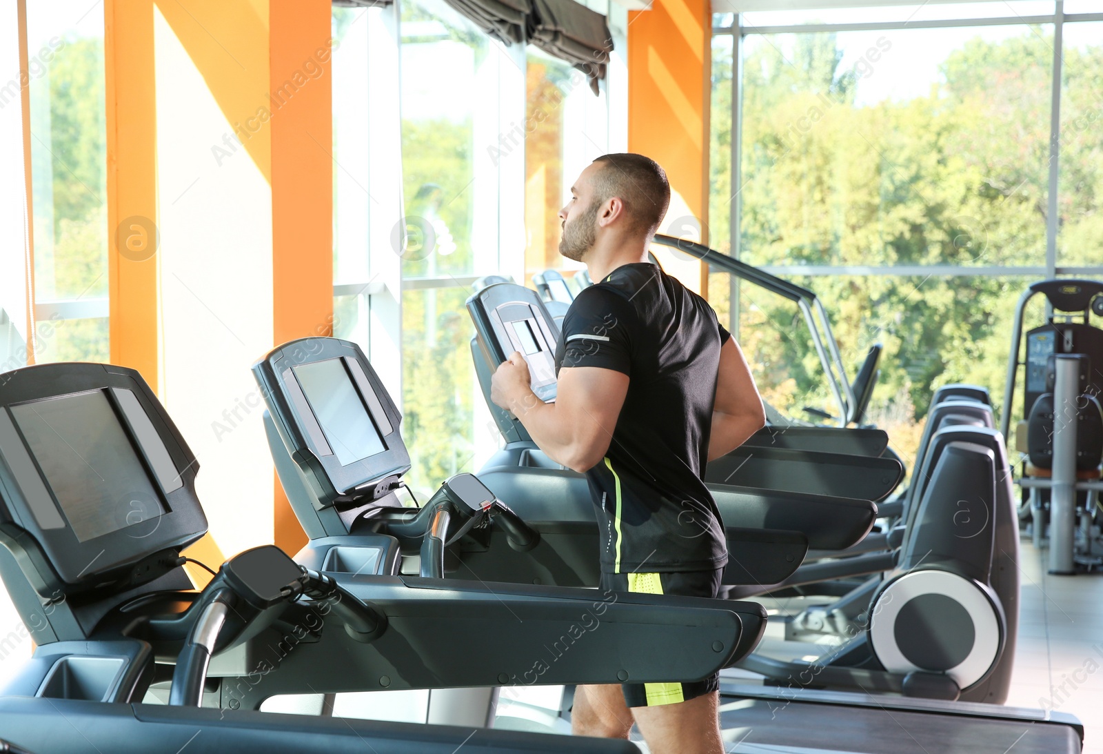 Photo of Strong young man on treadmill in gym