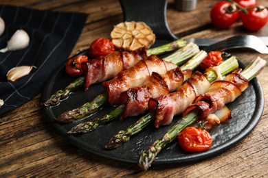 Photo of Oven baked asparagus wrapped with bacon on wooden table