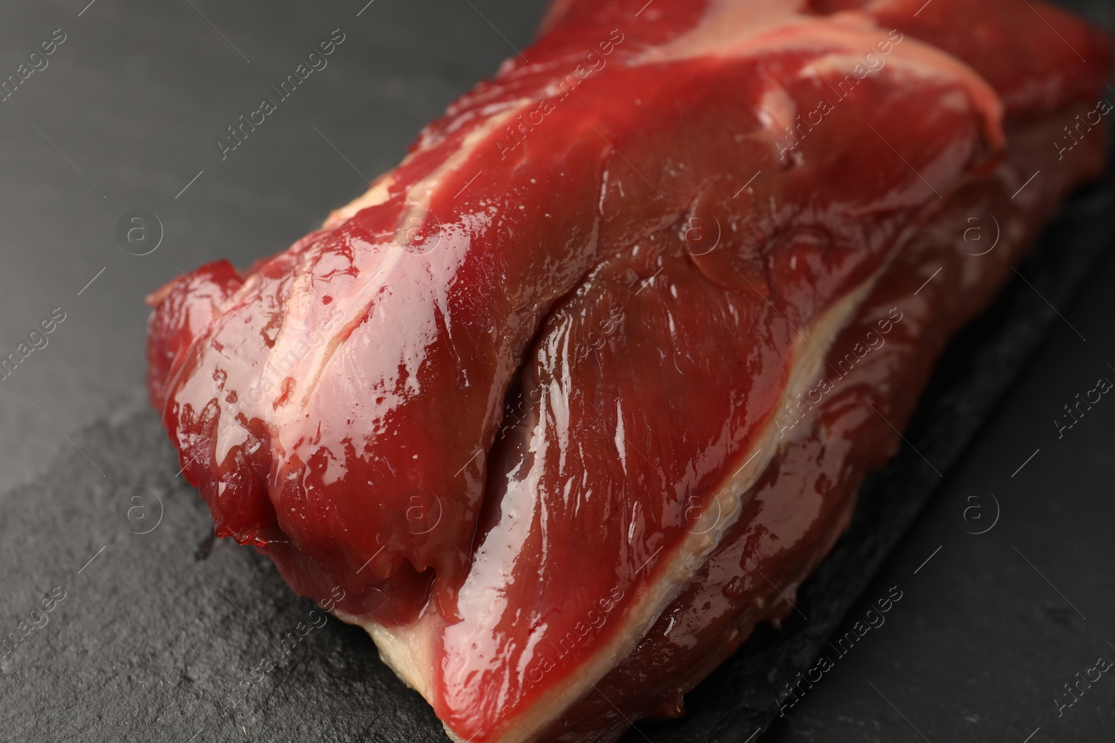 Photo of Piece of raw beef meat on black table, closeup