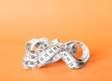 Photo of White measuring tape on orange background, closeup