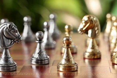 Photo of Golden pawn and silver knight on chess board against blurred background, closeup