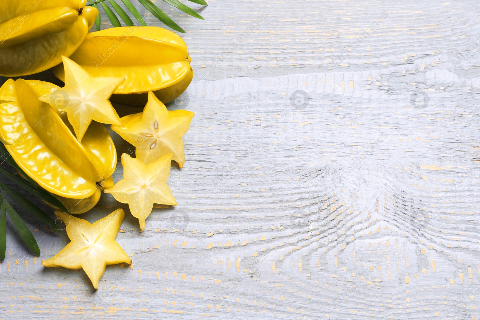 Photo of Delicious carambola fruits on light grey wooden table, flat lay. Space for text