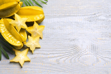 Photo of Delicious carambola fruits on light grey wooden table, flat lay. Space for text