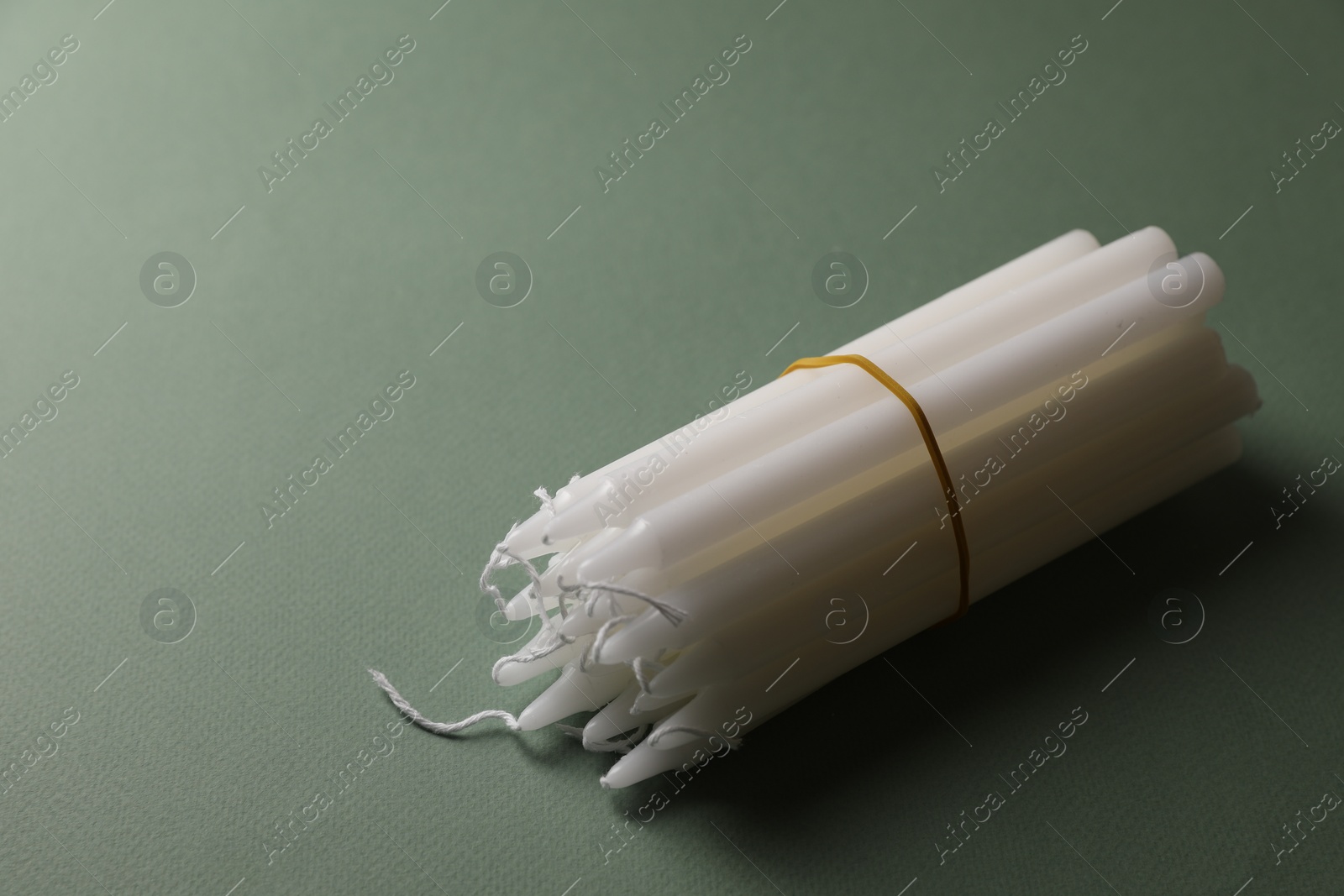 Photo of Many church wax candles on olive background, space for text