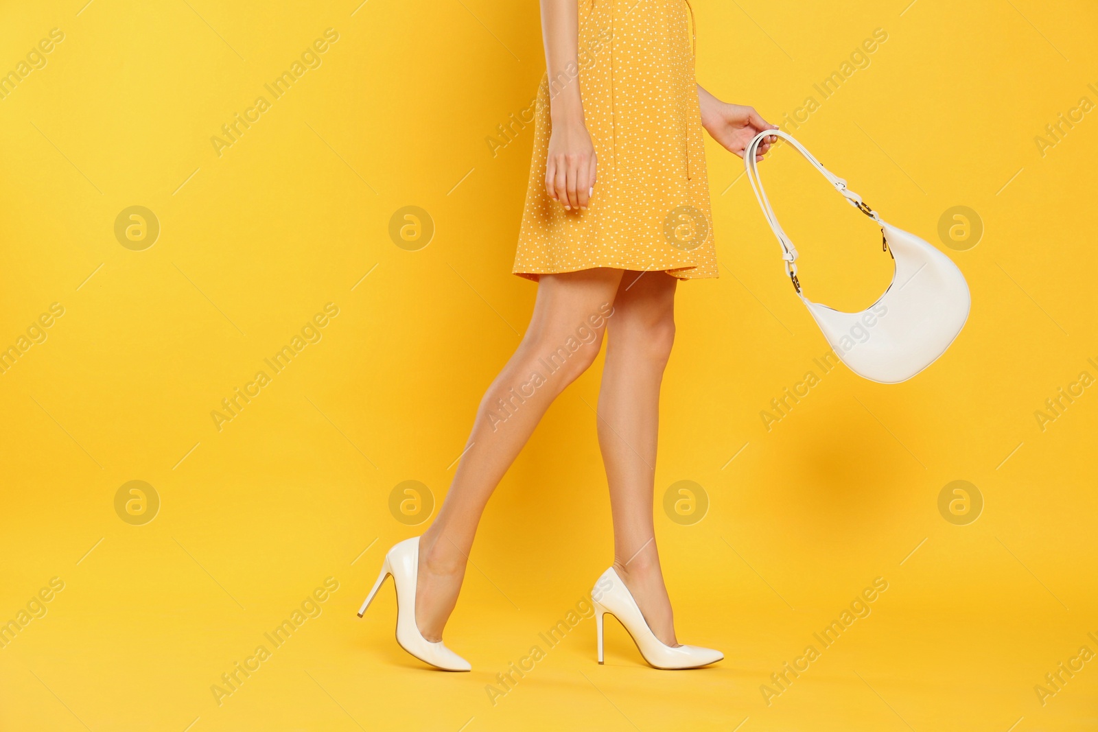 Photo of Woman with stylish bag on yellow background, closeup