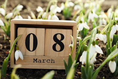 Wooden block calendar with date 8th of March among beautiful snowdrops outdoors. International Women's Day