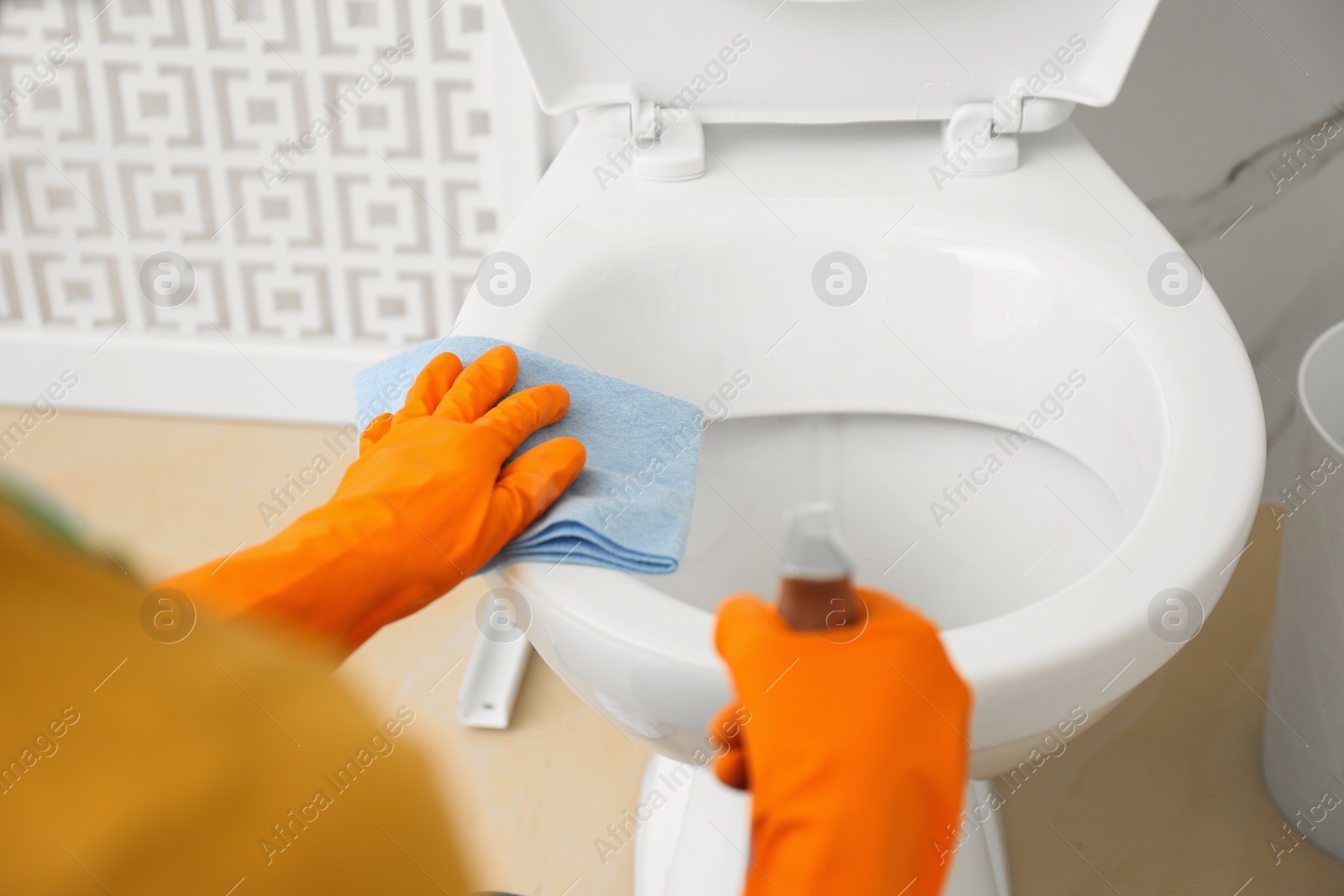 Photo of Woman cleaning toilet bowl in bathroom, closeup