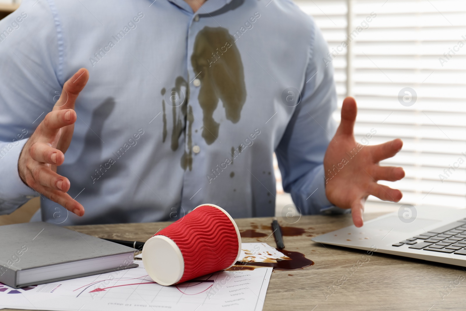 Photo of Man with spilled coffee over his workplace and shirt, closeup