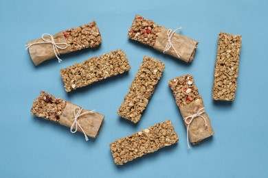 Photo of Different tasty granola bars on light blue background, flat lay