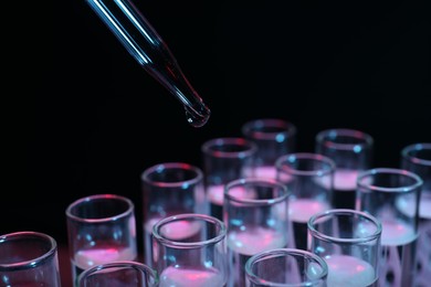 Photo of Dripping reagent into test tube on black background, closeup. Laboratory analysis