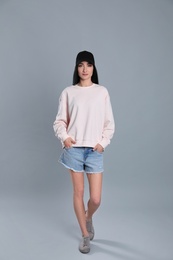 Full length portrait of young woman in sweater on grey background. Mock up for design