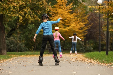 Cute children roller skating in autumn park