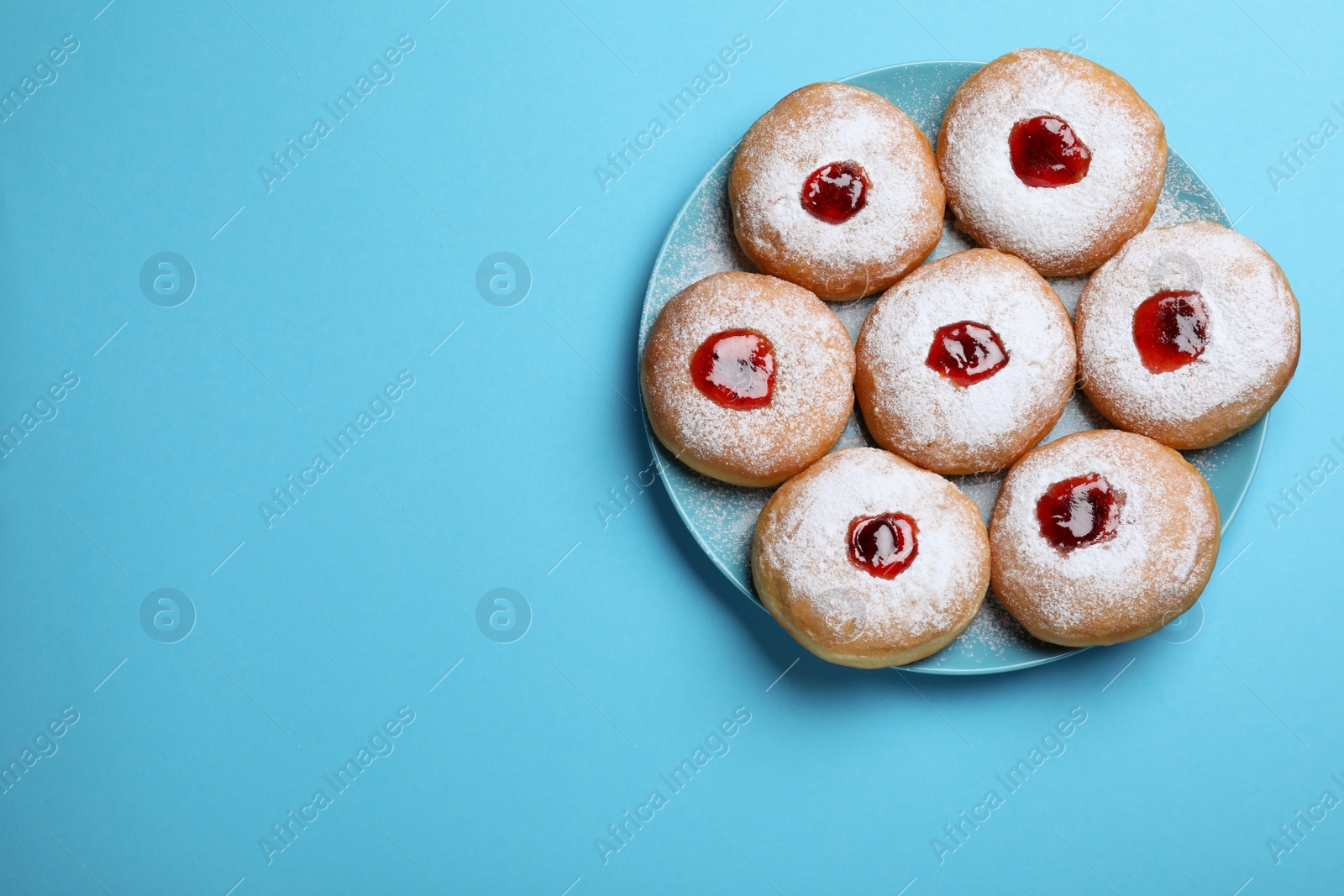 Photo of Hanukkah doughnuts with jelly and sugar powder served on blue background, top view. Space for text