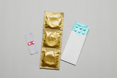 Contraception choice. Pills and condoms on light grey background, flat lay