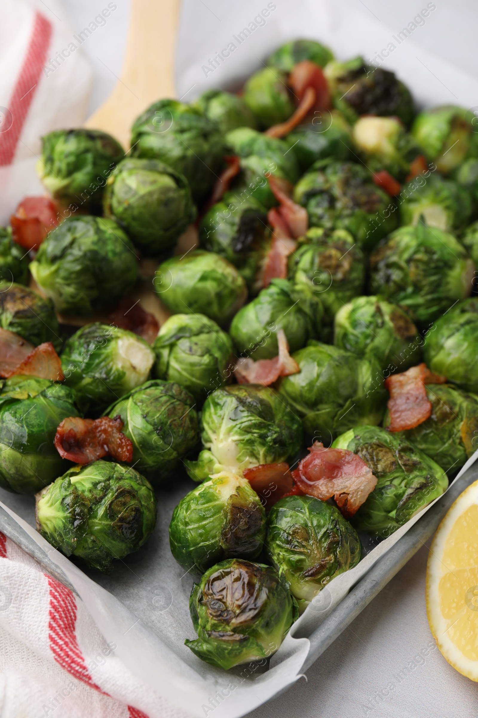 Photo of Delicious roasted Brussels sprouts and bacon in baking dish on table, closeup