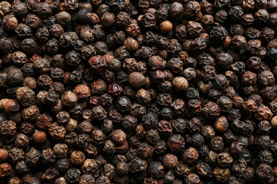 Photo of Many black peppercorns as background, top view