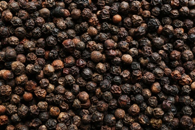 Many black peppercorns as background, top view