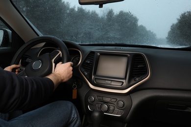 Photo of Young man driving car along winter forest, closeup