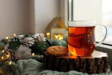 Photo of Cup of tea, cookie and Christmas decor on windowsill indoors