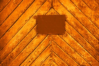 Image of Textured orange wooden surface with stained signboard as background
