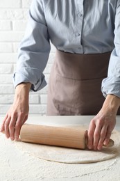 Photo of Woman rolling raw dough at table, closeup