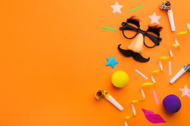 Flat lay composition with clown's accessories on orange background. Space for text