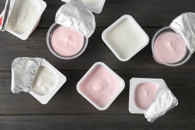 Photo of Plastic cups with tasty yogurt on wooden background, top view