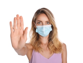 Woman in protective face mask showing stop gesture on white background. Prevent spreading of coronavirus