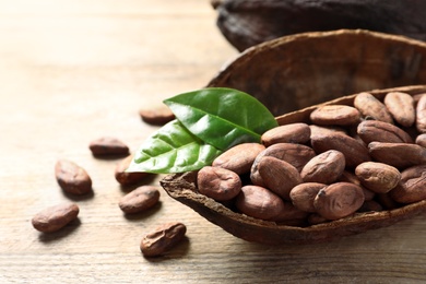 Photo of Half of cocoa pod with beans on wooden table, closeup