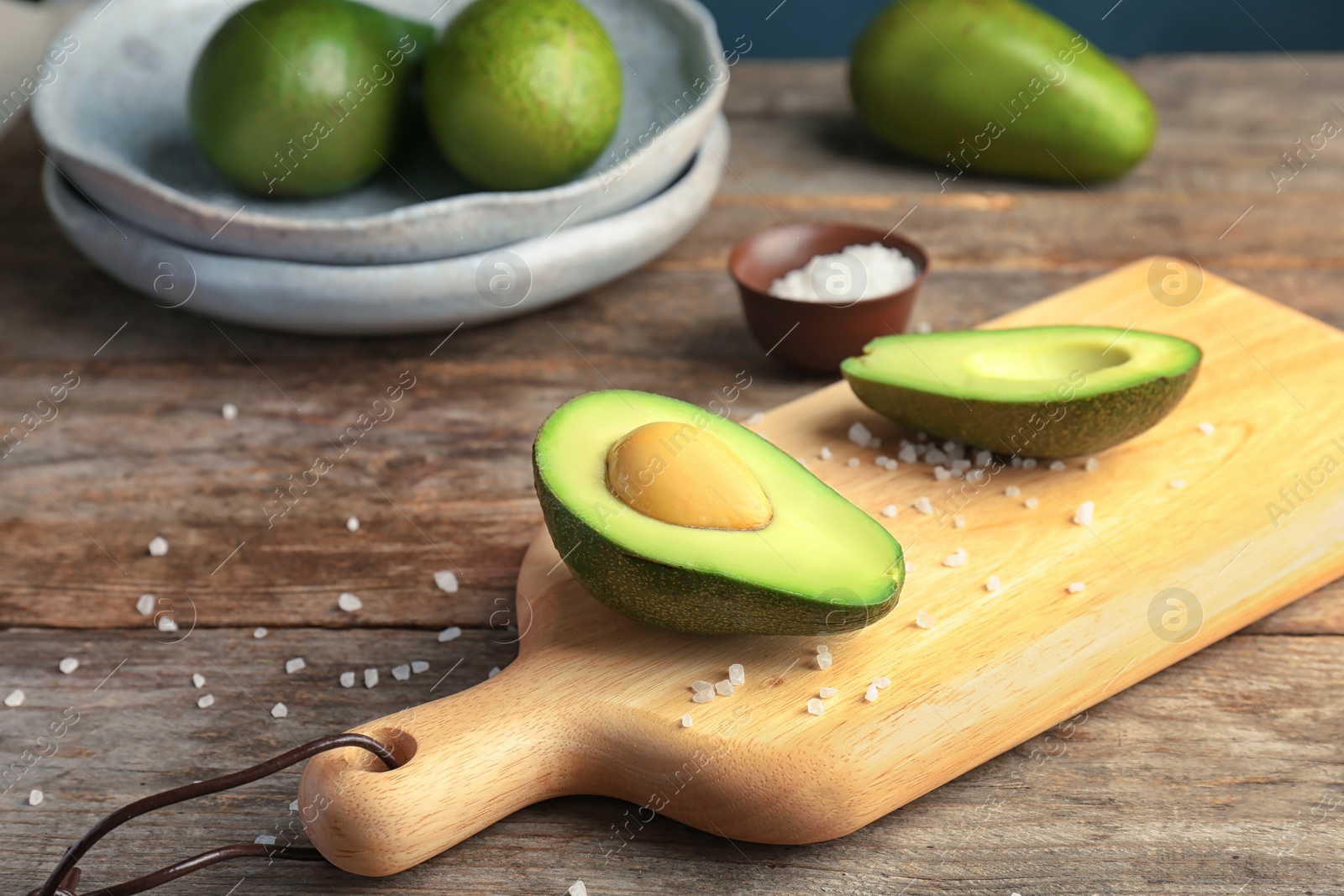 Photo of Wooden board with cut avocado on table