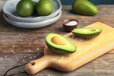 Photo of Wooden board with cut avocado on table