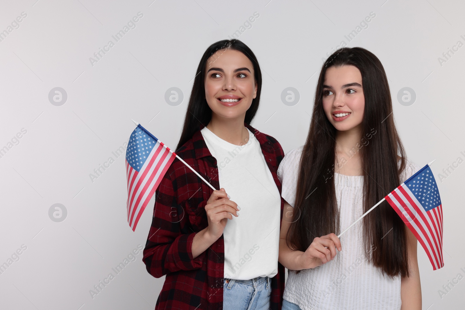 Photo of 4th of July - Independence Day of USA. Happy woman and her daughter with American flags on white background, space for text