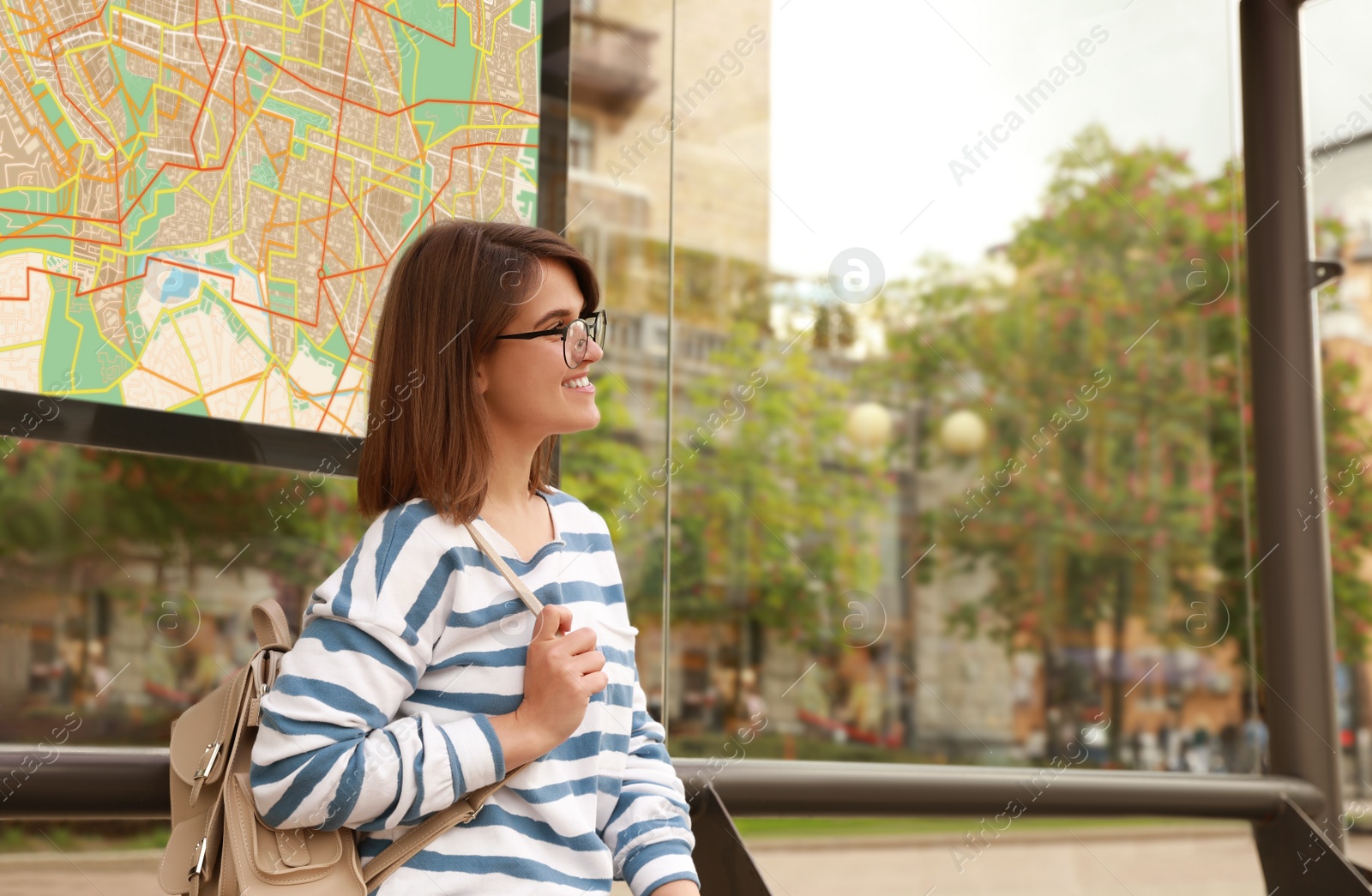 Image of Young woman waiting for public transport at bus stop