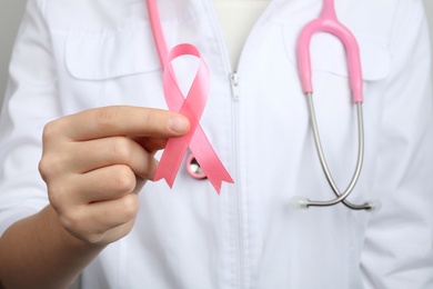 Photo of Doctor holding pink ribbon, closeup. Breast cancer awareness