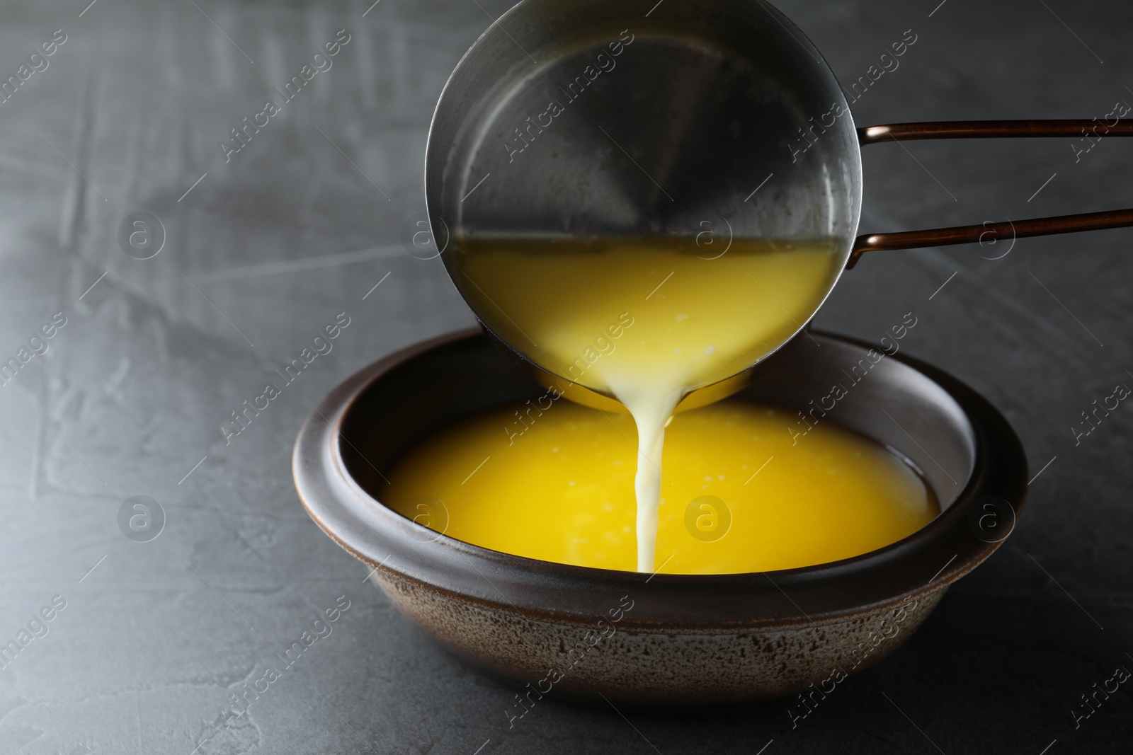 Photo of Pouring clarified butter into bowl on black table