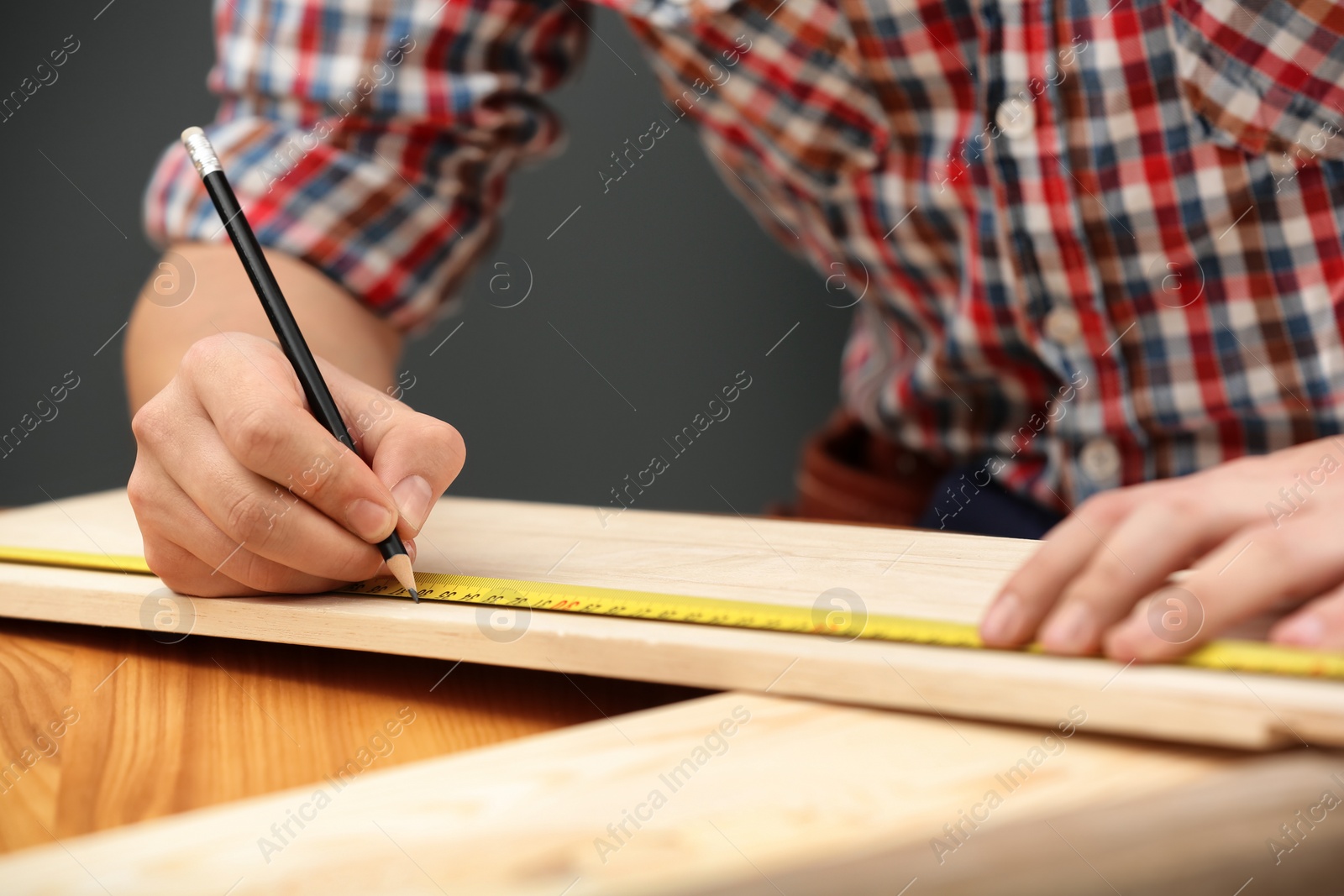 Photo of Young working man making marks on timber indoors, closeup. Home repair