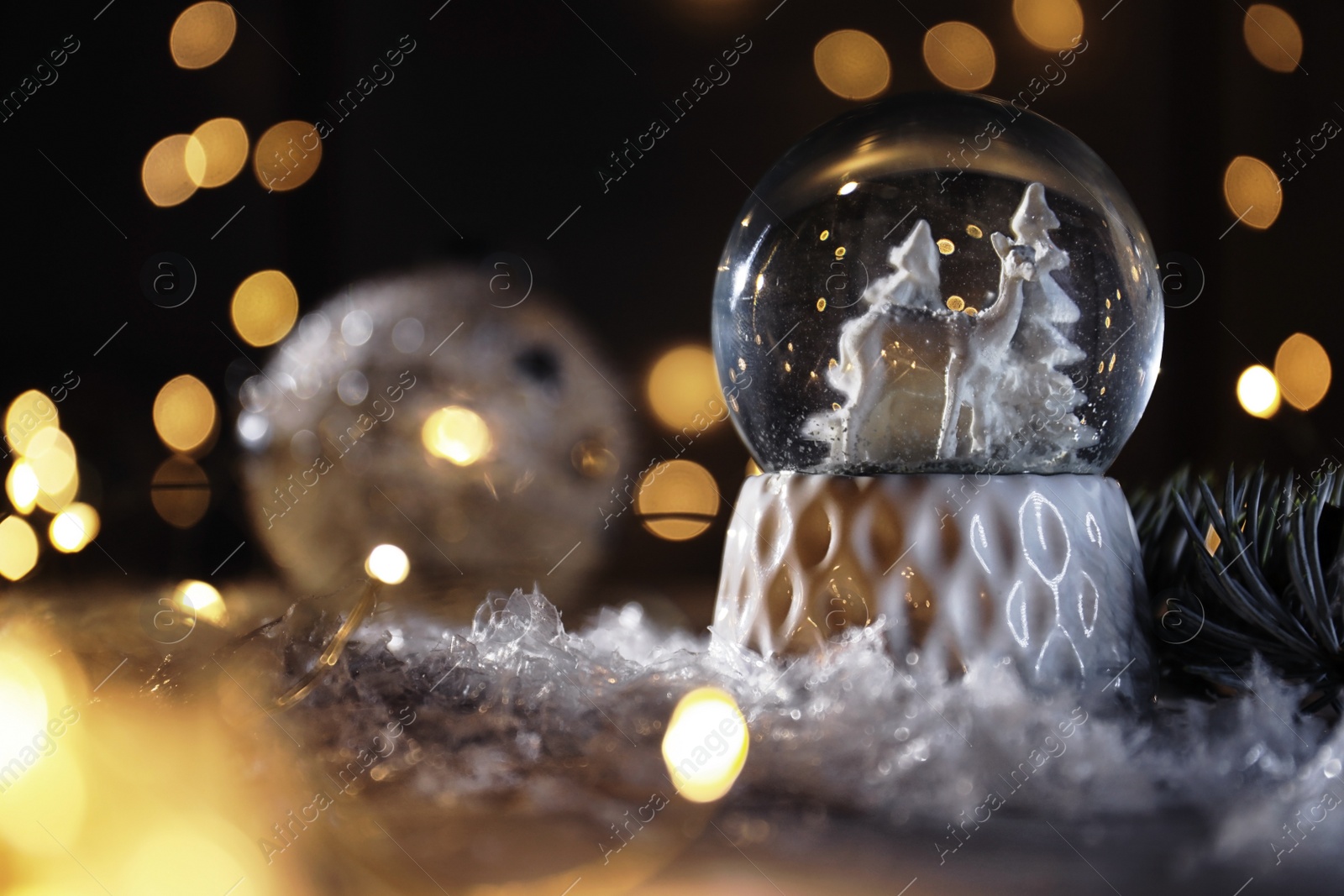Photo of Christmas glass globe with artificial snow on table against blurred background. Space for text