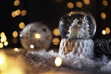 Christmas glass globe with artificial snow on table against blurred background. Space for text