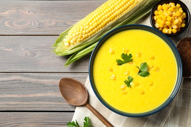 Photo of Delicious creamy corn soup served on wooden table, flat lay