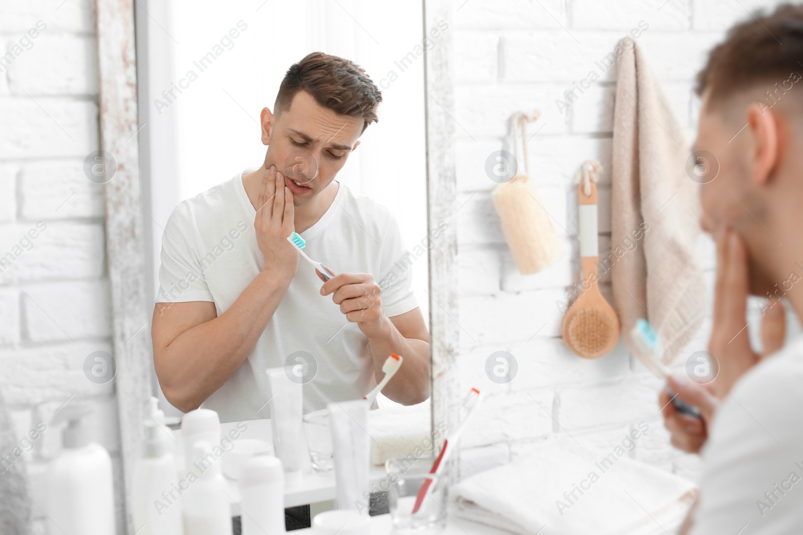 Photo of Young man with sensitive teeth in bathroom