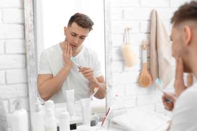 Young man with sensitive teeth in bathroom