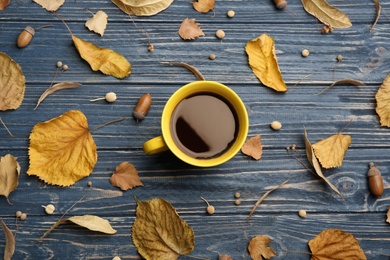 Cup of hot drink and autumn leaves on blue wooden table, flat lay. Cozy atmosphere