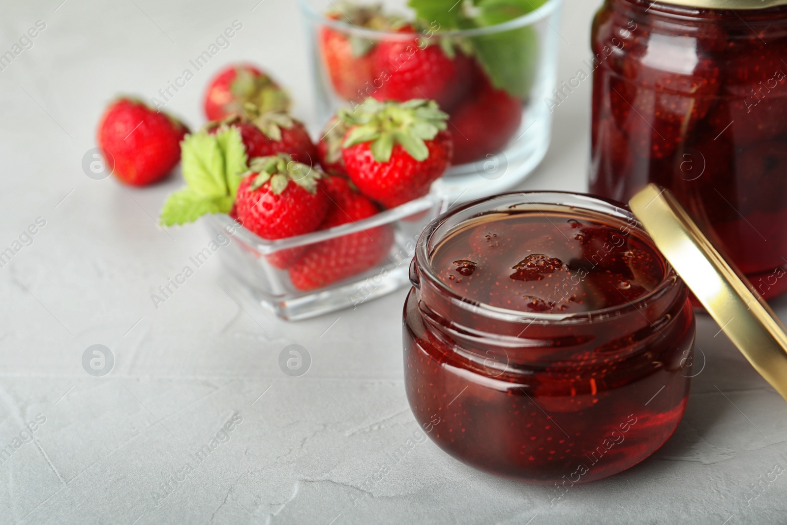 Photo of Delicious pickled strawberry jam and fresh berries on light table. Space for text