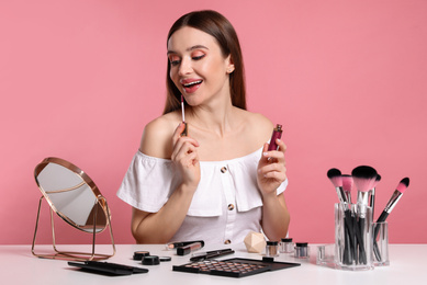 Beauty blogger applying lipgloss on pink background